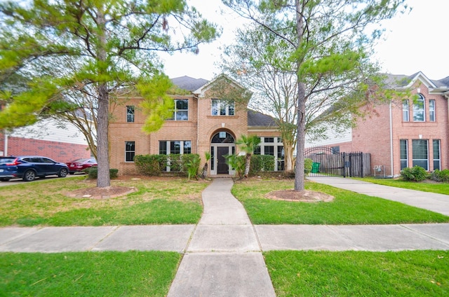 view of front of house featuring a front yard, a gate, and brick siding