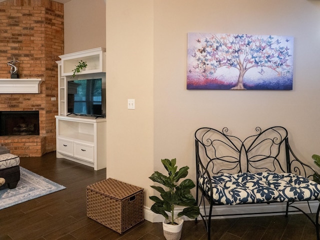 bedroom featuring a brick fireplace, dark wood finished floors, and baseboards