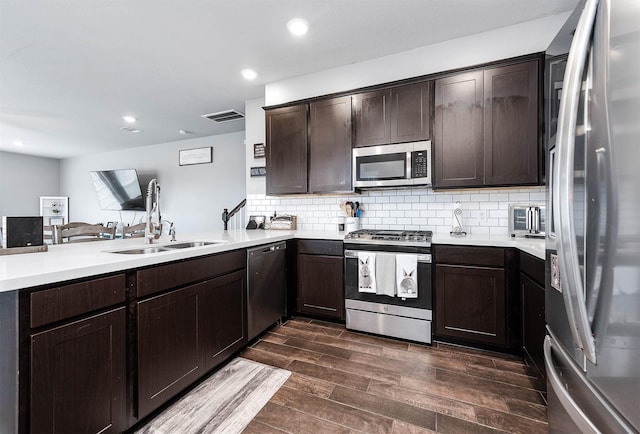 kitchen with visible vents, a peninsula, a sink, dark brown cabinetry, and appliances with stainless steel finishes