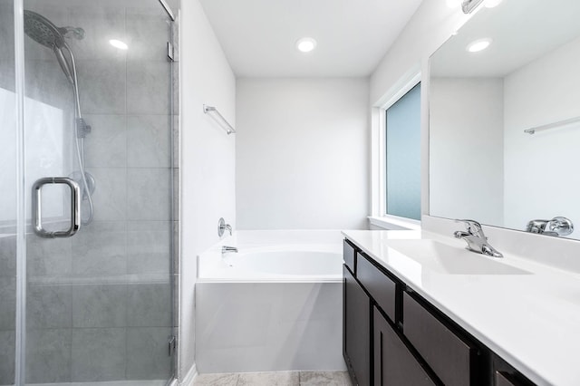 bathroom featuring a shower stall, vanity, and a garden tub