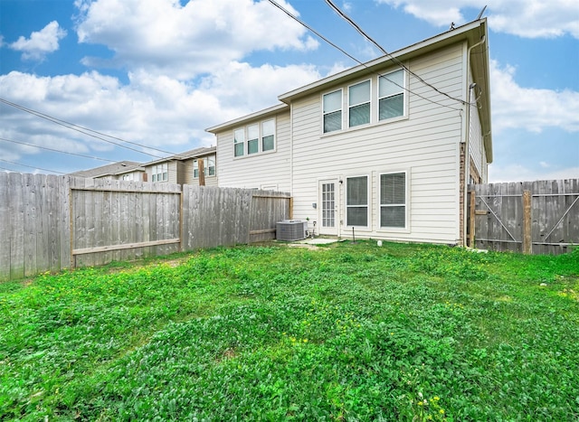 rear view of property with a yard, a fenced backyard, and central AC