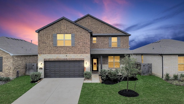 traditional home featuring an attached garage, concrete driveway, brick siding, and a front yard