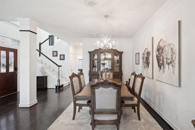 dining room featuring crown molding, baseboards, stairs, wood finished floors, and ornate columns