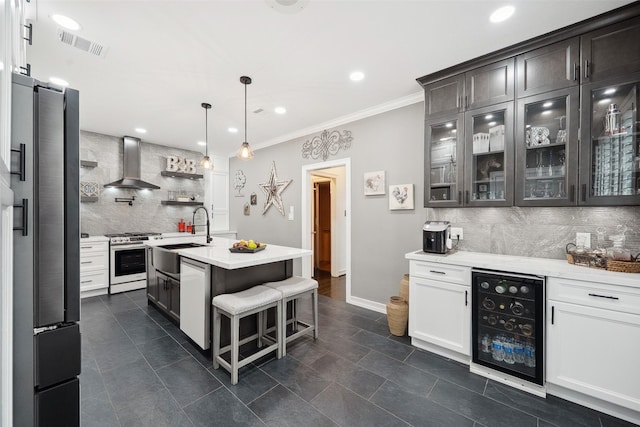 kitchen with appliances with stainless steel finishes, backsplash, wall chimney exhaust hood, wine cooler, and a sink