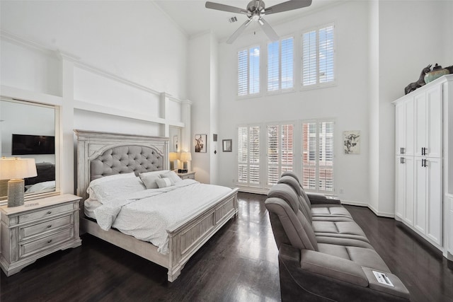 bedroom with a towering ceiling, baseboards, ornamental molding, dark wood-type flooring, and ceiling fan