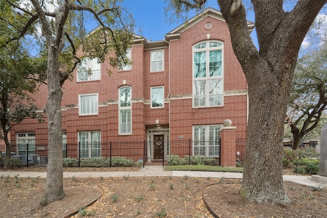 view of property featuring brick siding and fence