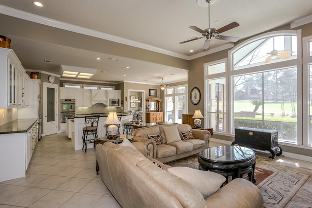 living area featuring ornamental molding, light tile patterned flooring, a ceiling fan, and a healthy amount of sunlight