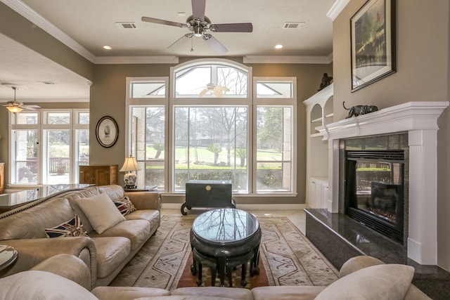 living area featuring a ceiling fan, a high end fireplace, visible vents, and crown molding