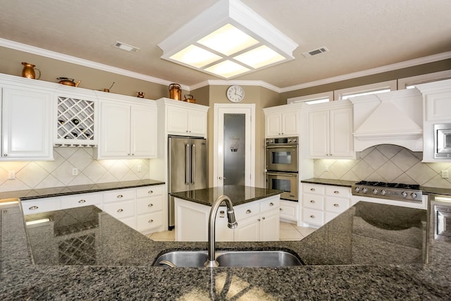 kitchen featuring custom exhaust hood, visible vents, appliances with stainless steel finishes, and a sink