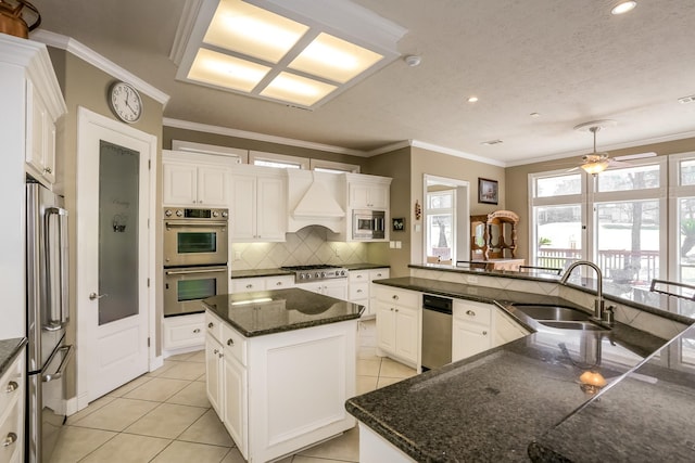 kitchen with decorative backsplash, a spacious island, custom range hood, stainless steel appliances, and a sink