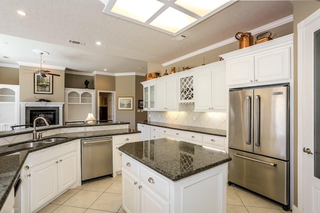 kitchen featuring ceiling fan, light tile patterned flooring, stainless steel appliances, a fireplace, and a sink