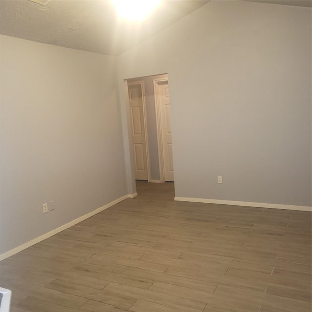 unfurnished room with light wood-type flooring and baseboards