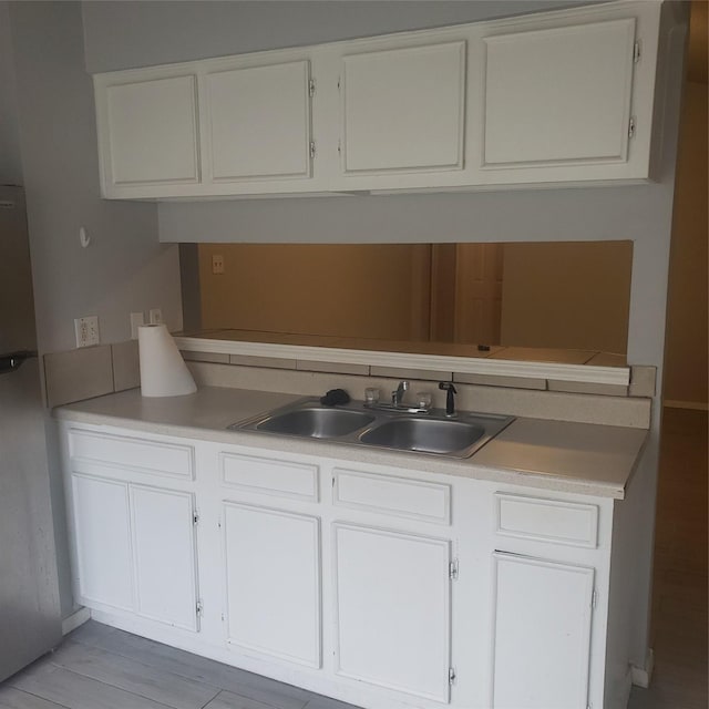 kitchen featuring light countertops, white cabinets, and a sink