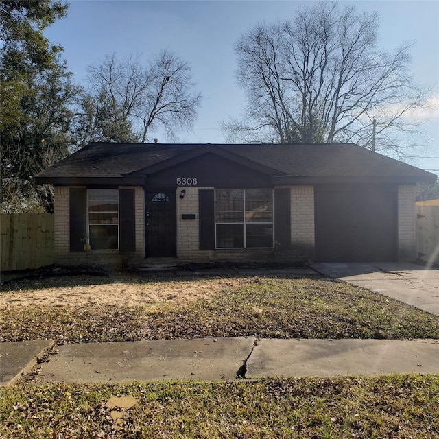 view of front of home with concrete driveway, brick siding, fence, and an attached garage