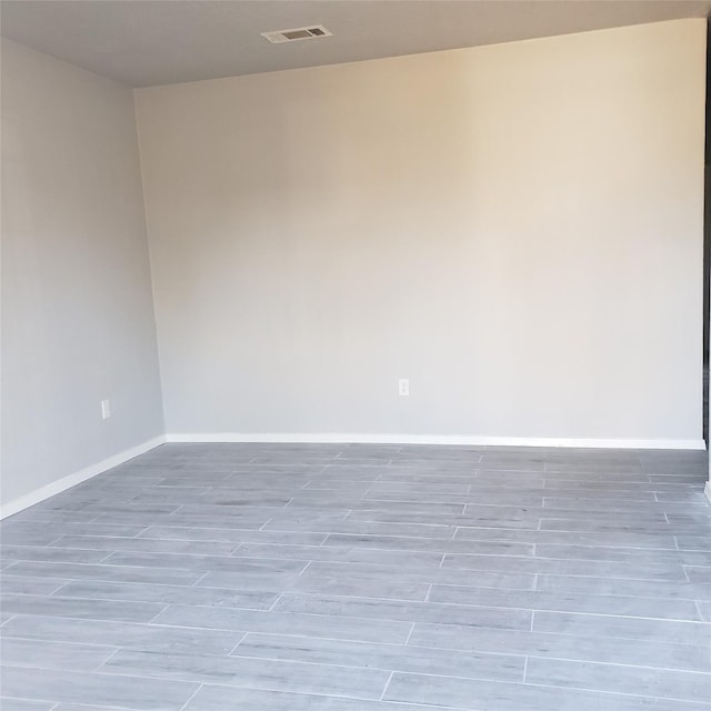 unfurnished room with wood tiled floor, visible vents, and baseboards