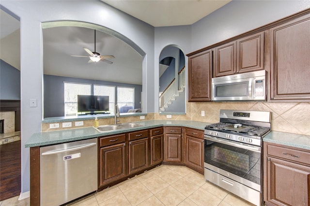 kitchen with ceiling fan, decorative backsplash, stainless steel appliances, and a sink