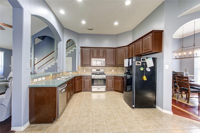 kitchen featuring appliances with stainless steel finishes, light tile patterned flooring, a sink, and backsplash