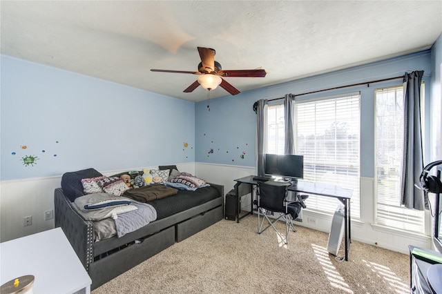 bedroom featuring a ceiling fan, carpet, and wainscoting