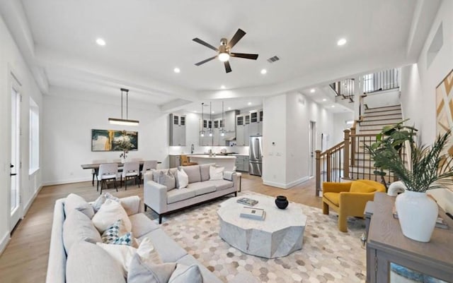 living room featuring baseboards, stairway, light wood-style flooring, and recessed lighting