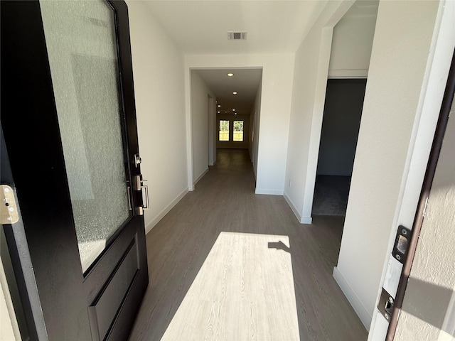 corridor featuring dark wood-style floors, visible vents, and baseboards