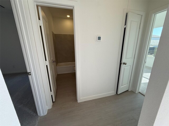 hallway featuring wood finished floors and baseboards