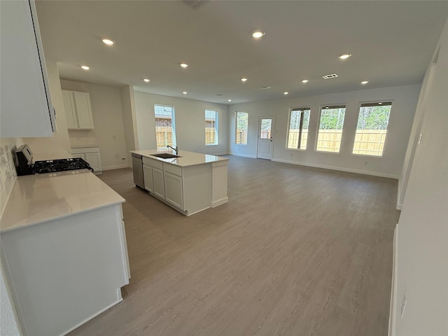 kitchen featuring range with gas stovetop, light wood-style floors, white cabinetry, and dishwasher