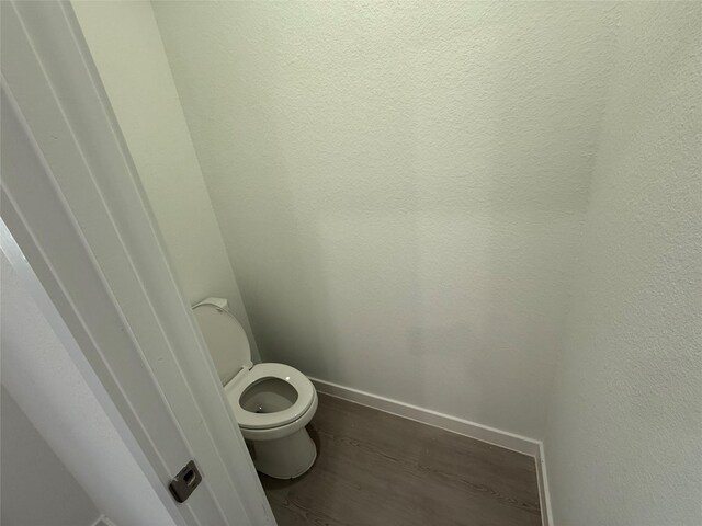 bathroom featuring toilet, baseboards, and wood finished floors