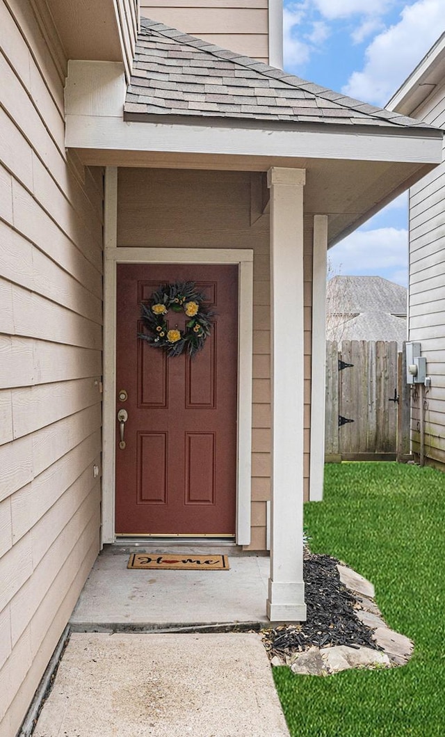 property entrance with fence and a shingled roof