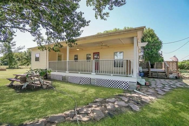 back of property with ceiling fan, a lawn, and a wooden deck