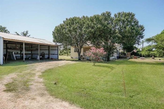 view of yard with dirt driveway, a pole building, and an outbuilding