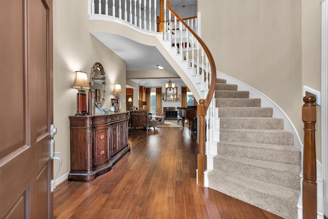 foyer entrance with stairs, a high ceiling, wood-type flooring, and baseboards