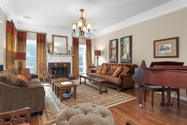 living room featuring a tile fireplace, wood finished floors, visible vents, an inviting chandelier, and crown molding