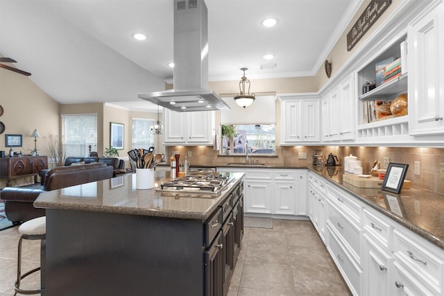 kitchen featuring island range hood, stainless steel gas cooktop, a kitchen island, white cabinetry, and open floor plan