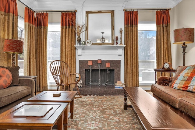 living area with a tiled fireplace and crown molding