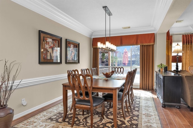 dining space featuring ornamental molding, light wood-type flooring, a chandelier, and visible vents