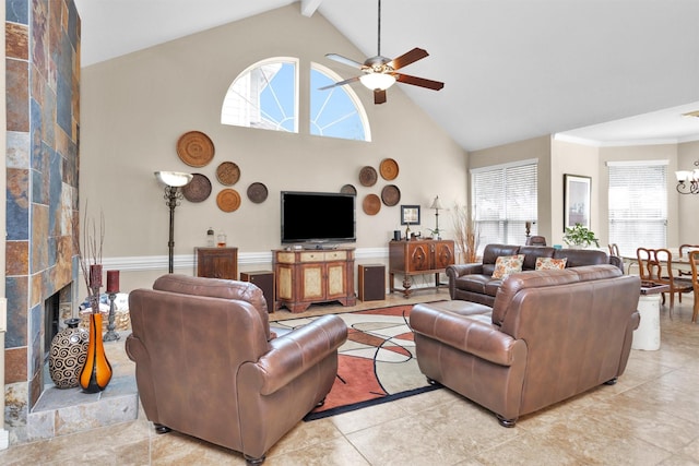 living area with high vaulted ceiling, a tile fireplace, crown molding, and ceiling fan with notable chandelier