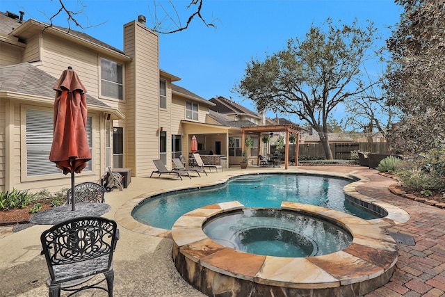 view of pool featuring a pool with connected hot tub, fence, and a patio