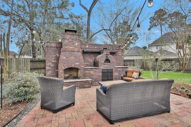 view of patio / terrace with an outdoor brick fireplace and a fenced backyard