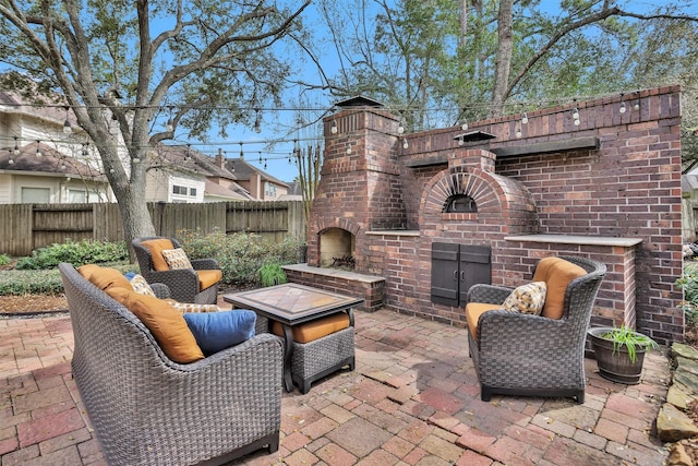 view of patio / terrace featuring an outdoor brick fireplace and fence