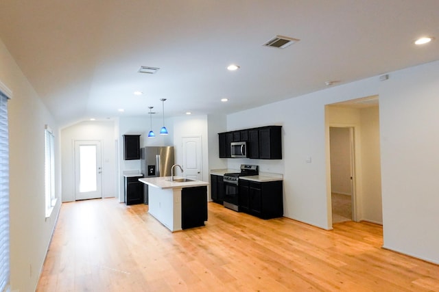 14428 Sugar Pines Dr, Conroe, TX 77302 - kitchen with a sink, light wood-style floors, dark cabinetry, stainless steel appliances, and visible vents