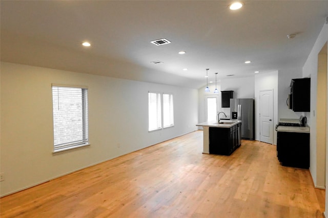 14428 Sugar Pines Dr, Conroe, TX 77302 - kitchen with visible vents, light countertops, stainless steel fridge with ice dispenser, dark cabinetry, and an island with sink
