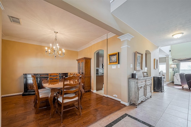 dining space featuring arched walkways, baseboards, light wood-style flooring, and ornate columns