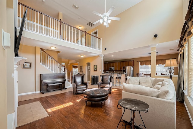 living area featuring ornate columns, wood-type flooring, stairway, and a ceiling fan