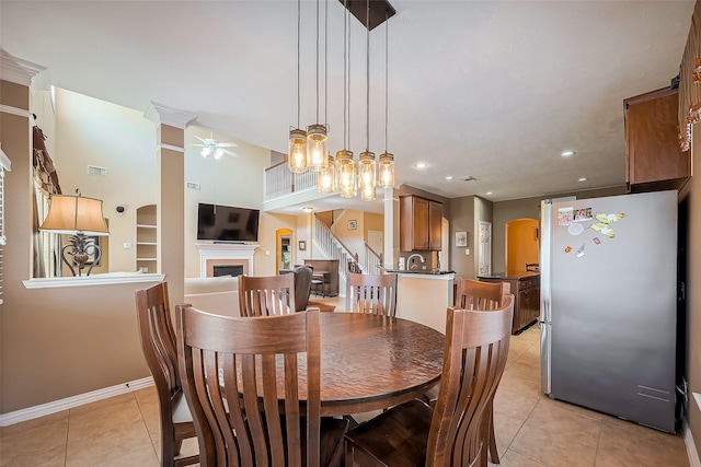 dining space with light tile patterned flooring, a fireplace, visible vents, baseboards, and stairway