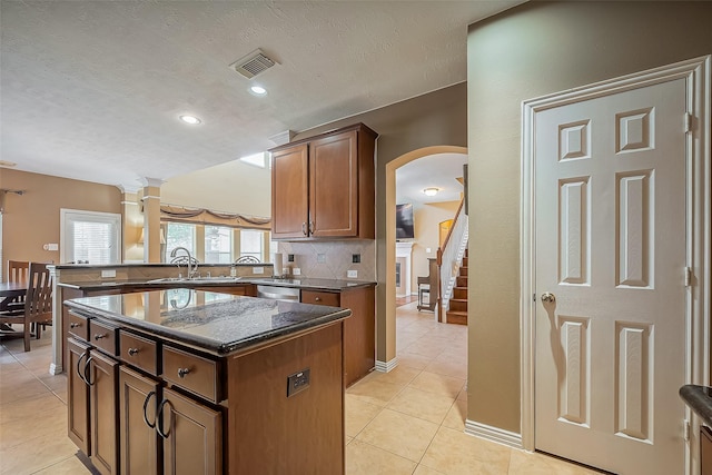 kitchen with visible vents, decorative backsplash, a peninsula, a sink, and light tile patterned flooring