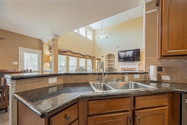 kitchen featuring backsplash, brown cabinetry, a sink, ceiling fan, and a peninsula