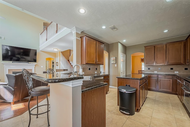 kitchen with visible vents, arched walkways, dark stone countertops, a center island, and a peninsula