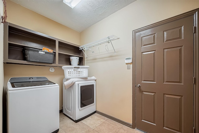 laundry area with laundry area, light tile patterned floors, washer and clothes dryer, and a textured ceiling