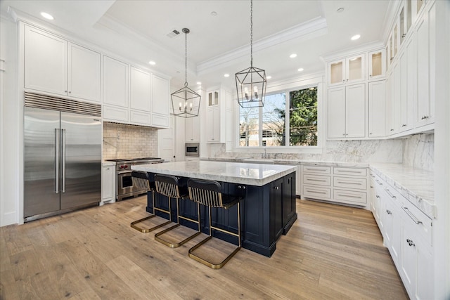 kitchen featuring a center island, white cabinetry, a raised ceiling, and built in appliances