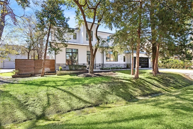 view of front of property featuring stucco siding, an attached garage, stone siding, driveway, and a front lawn